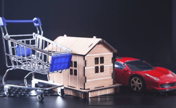 Shopping cart with house model on laptop keyboard. - Photo, Image