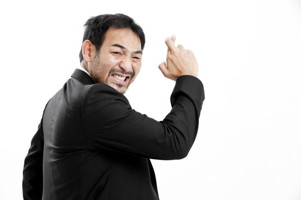 Superstitious - Asian business man with crossed fingers over white background - Fotografie, Obrázek