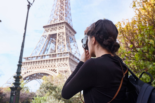 Beautiful girl posing with a camera taking pictures of the Eiffel Tower. Paris, Champ de Mars - Photo, Image