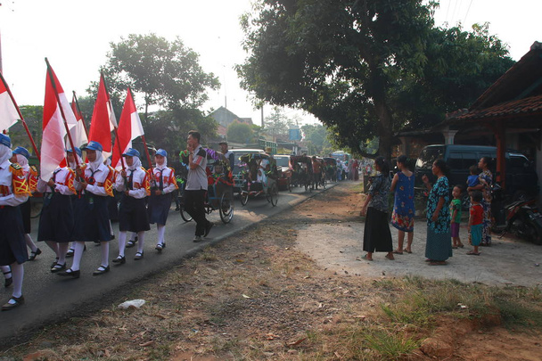 Жители и студенты празднуют годовщину окончания исламской школы с шествиями по пути. С музыкальными выступлениями и поднятием флага, Батанг / Индонезия, 22 июня 2019 г.
 - Фото, изображение