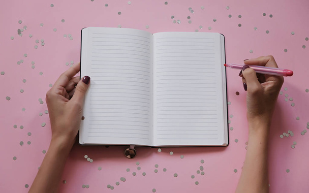 Frauenhände mit perfekter Maniküre mit Textmarker und Notizblock als Mockup für Ihr Design. rosa Hintergrund, flacher Lay-Stil. - Foto, Bild