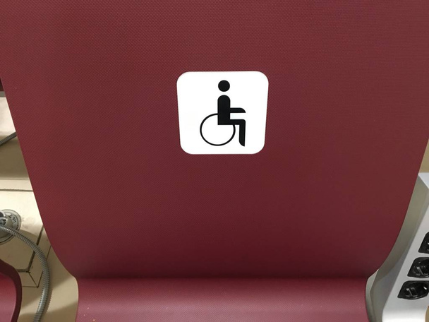 place for invalid. seats for the disabled, chairs in the hall for special people. A row of burgundy chairs for people with disabilities. airport lounge - Photo, Image