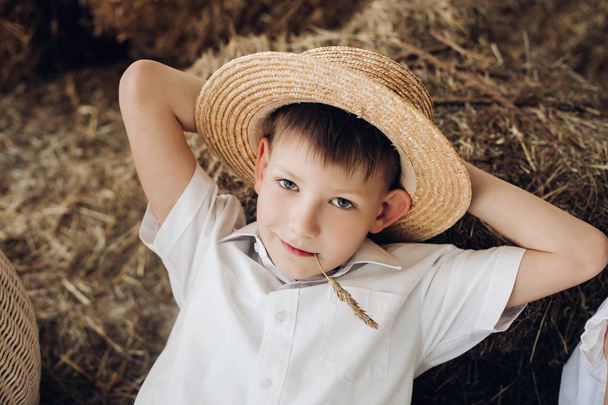Cool boy lying on hay and resting in village - Foto, afbeelding