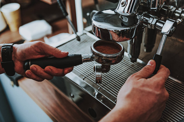 Filter holder full of coffee and barista touching it - 写真・画像