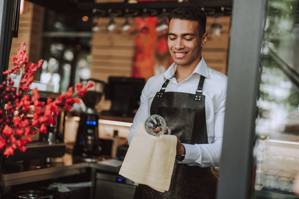 Handsome barman wiping glass with cleaning cloth - Foto, Imagen