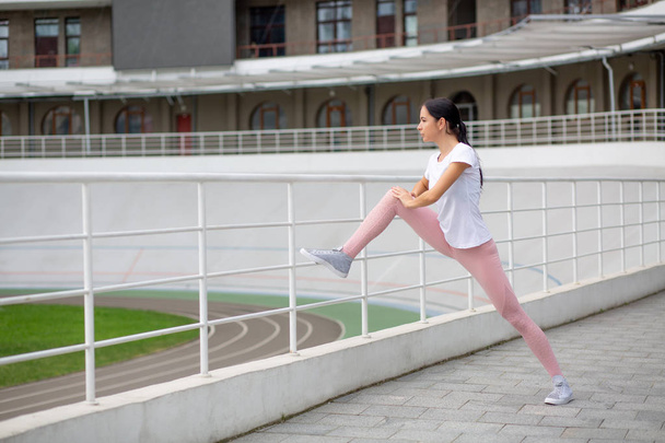 wunderschöne gebräunte sportliche Frau dehnt sich vor dem Laufen schief h - Foto, Bild
