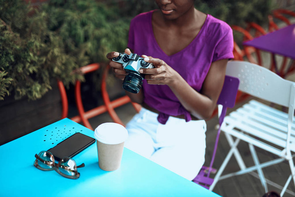 Спокойная афро-американка держит камеру в кафе на открытом воздухе
 - Фото, изображение