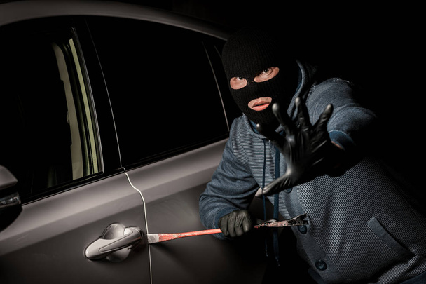 ladrón masculino va a abrir la puerta del coche con una palanca
. - Foto, Imagen