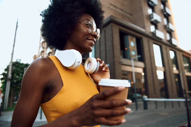 Радостная юная леди держит кофе на открытом воздухе
 - Фото, изображение