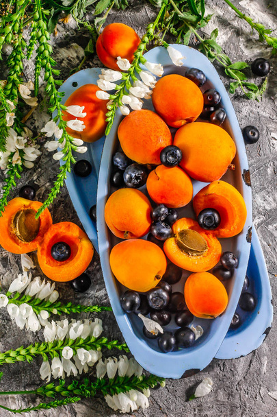 A sárgabarack és áfonya a konzervtálcát egy konkrét hátteret. Nyári gyümölcsök és bogyók. - Fotó, kép