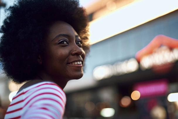 Mulher afro-americana bonita olhando para longe e sorrindo
 - Foto, Imagem