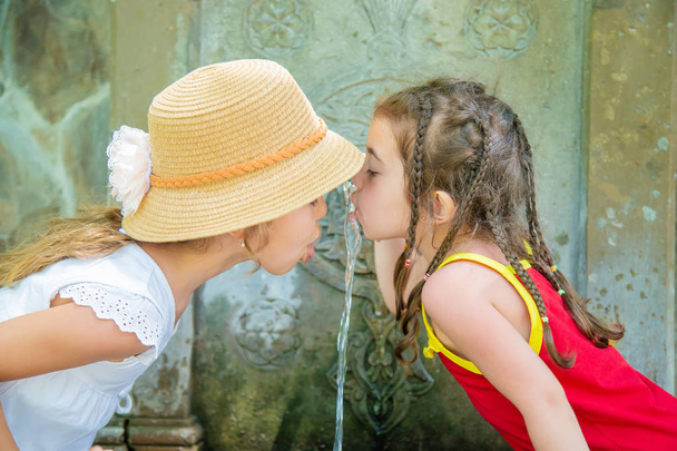 子供たちはジョージア州ボルホミの泉から水を飲みます。選択フォーカス. - 写真・画像