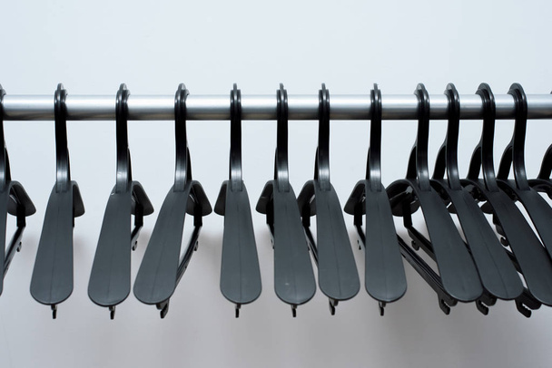 black plastic hangers hang on a light background. many different hangers. floor coat rack - Photo, Image