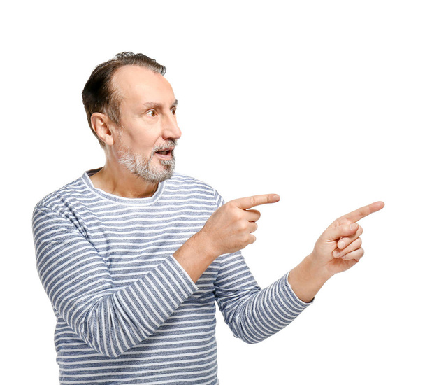 Portrait of emotional mature man pointing at something on white background - Foto, Imagem