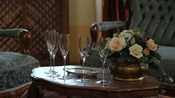 Primer plano de una mesa a la antigua en un restaurante con un ramo y glasos para champán
 - Imágenes, Vídeo