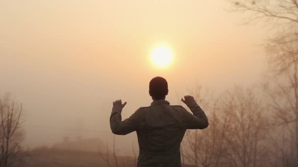 Happy successful man celebrating during sunrise or sunset. Happy and Free. Guy raises his hands and rejoices agains the sun. Success concept - Footage, Video