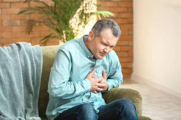 Hombre maduro que sufre de un ataque al corazón en casa
 - Foto, imagen