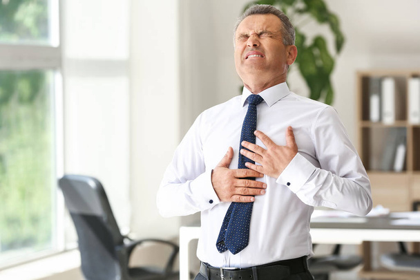 Homme mûr souffrant d'une crise cardiaque au bureau
 - Photo, image