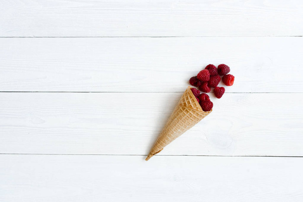 Каскад свежей малины в вафельном конусе мороженого на белом фоне. Кафе или меню ресторана. Копирование пространства
 - Фото, изображение