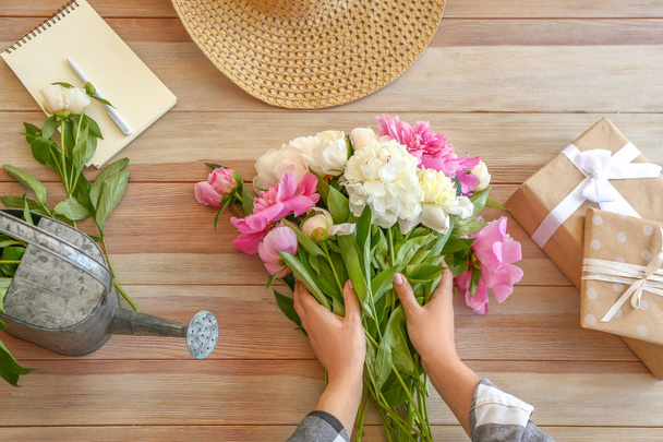 Woman making bouquet of beautiful peonies at table - Photo, image