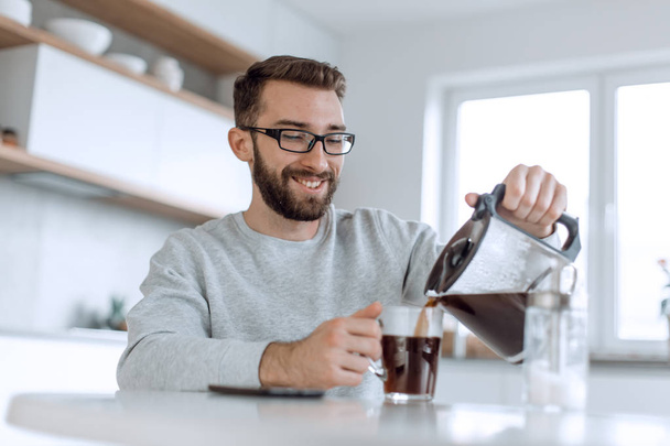 vonzó férfi tölt magának egy csésze reggeli kávét - Fotó, kép