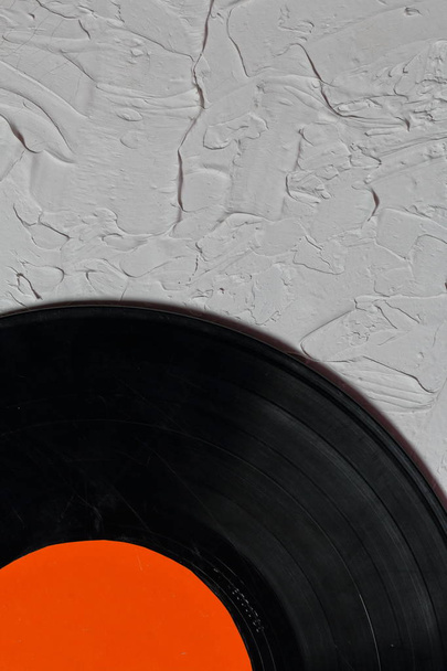 Old vinyl record. Worn and dirty. It lies on the surface covered with decorative plaster. - 写真・画像