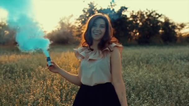Fiatal vonzó barna lány szoknya egy kék füst bomba a pályán. Lány szórakozik nevetve élvezi és örvénylő a füst ellen naplemente. - Felvétel, videó