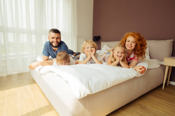 Delighted happy family resting together on the bed - Foto, Imagem