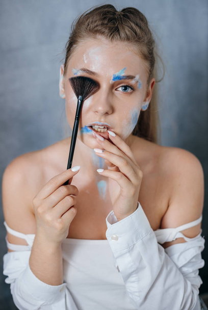 Creative fashion beauty portrait of a beautiful young blond woman with a brush for cosmetics - Photo, image