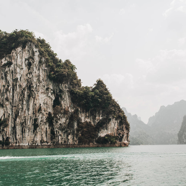 Εξωτικά και τροπικά σκούρα πράσινα νησιά με βράχους και πράσινη λίμνη στη λίμνη Cheow LAN, Καο Φανγκ, Μπαν τα Κουν, Ταϊλάνδη. Ταξιδιωτικές διακοπές και περιπέτεια. - Φωτογραφία, εικόνα