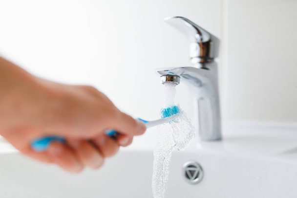 main tenant la brosse à dents sous l'eau courante du robinet - Photo, image