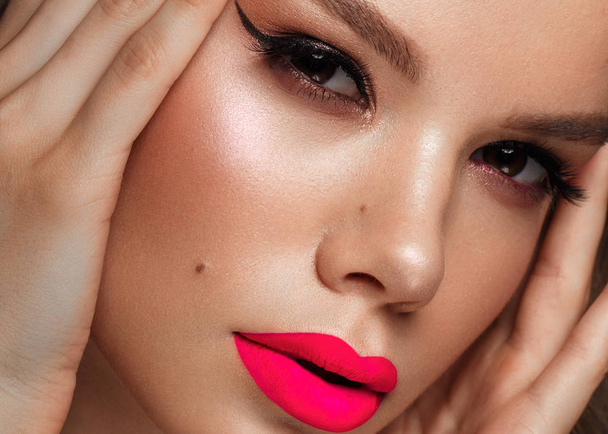 Beautiful young woman with bright makeup and neon pink lips. Beauty face. Photo taken in the studio - Zdjęcie, obraz