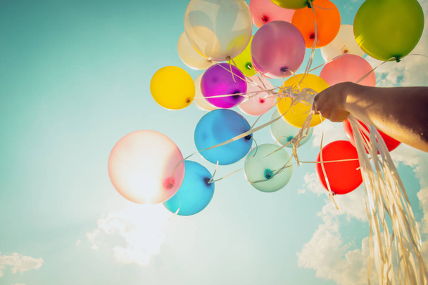 Χέρι εκμετάλλευση πολύχρωμα μπαλόνια που γίνεται με ένα ρετρό vintage instagram εφέ φίλτρου. - Φωτογραφία, εικόνα