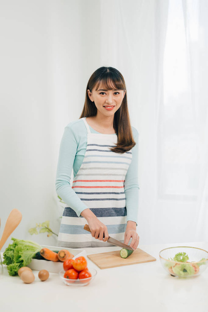 Young woman cutting vegetables in the kitchen. Woman cooking healthy food.  - Foto, Bild