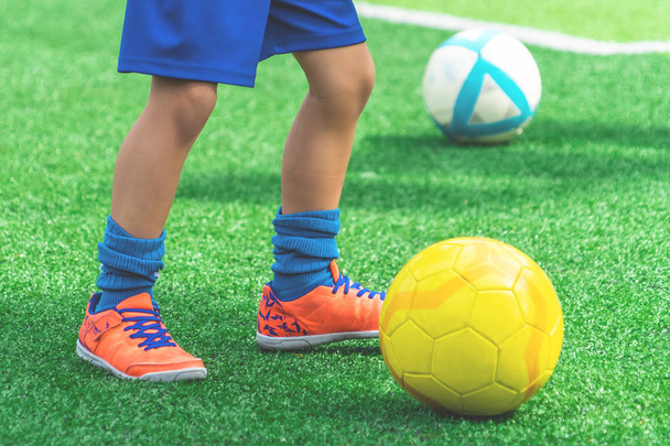 Niño pies es driblando pelota de fútbol en un campo
 - Foto, Imagen