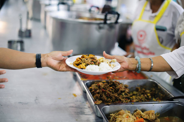 Chudí lidé od dobrovolníka dostávají jídlo: koncept dárcovství potravin - Fotografie, Obrázek