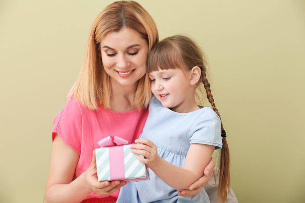 Little girl greeting her mother on color background - Foto, afbeelding
