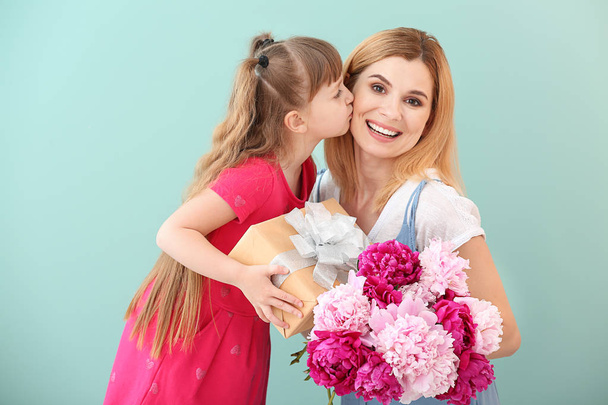 Little girl greeting her mother on color background - Foto, imagen