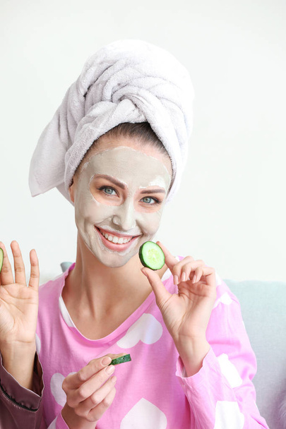 Beautiful young woman with facial mask and cucumber slices at home - Foto, immagini