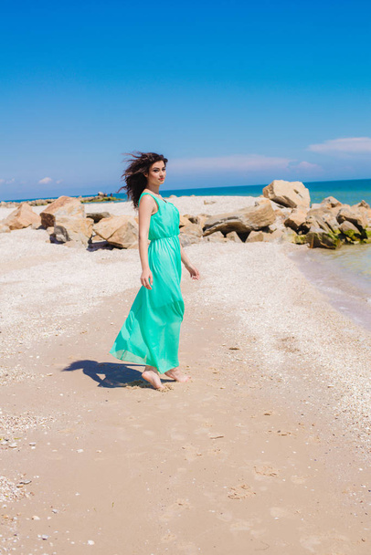 Young beautiful girl in a long dress on the beach  - Фото, изображение