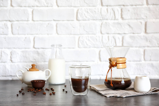 Glass of hot coffee on table near brick wall - Zdjęcie, obraz