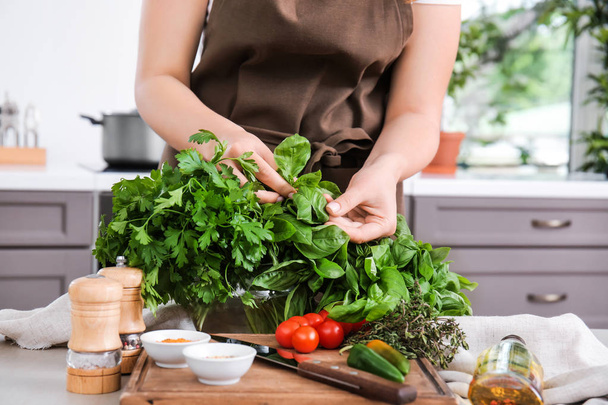 A konyhában friss fűszernövényeket is tartalmazó nő - Fotó, kép