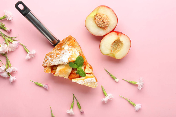 Piece of tasty peach pie and flowers on color background - Zdjęcie, obraz