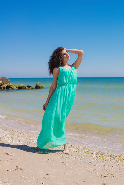 Young beautiful girl in a long dress on the beach  - 写真・画像