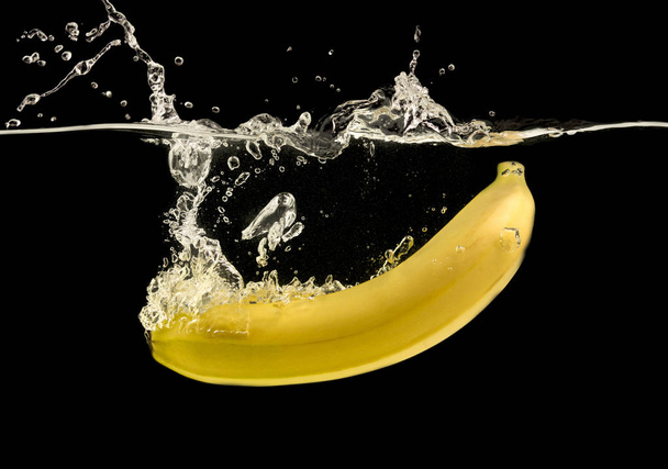 Kypsä keltainen banaani roiskuu kirkkaaseen veteen
 - Valokuva, kuva