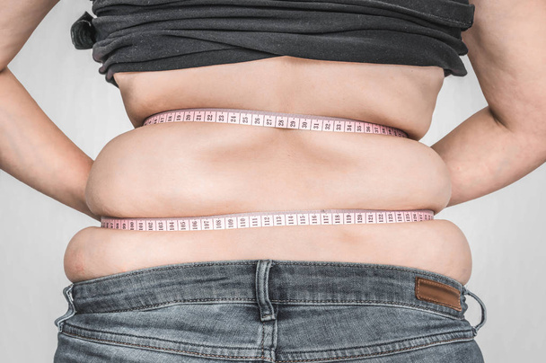 Mujer con sobrepeso con cinta está midiendo la grasa en el vientre
 - Foto, Imagen