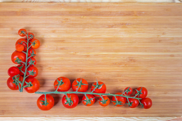 Background of cherry tomato clusters on the bamboo cutting board - Photo, Image