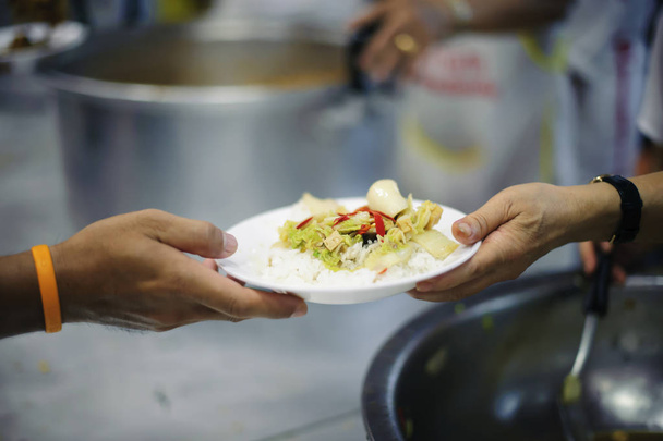 Mãos de voluntários serve comida gratuita para os pobres e necessitados na cidade
 - Foto, Imagem