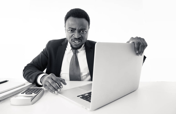 Angry and desperate african american entrepreneur businessman shouting at computer feeling tired and overworked at desk in People, Stress, Technology and Overtime concept isolated in white background. - Fotografie, Obrázek