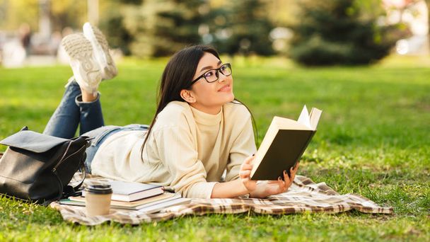 Estudiante asiático leyendo libro, preparándose para los exámenes al aire libre
 - Foto, Imagen